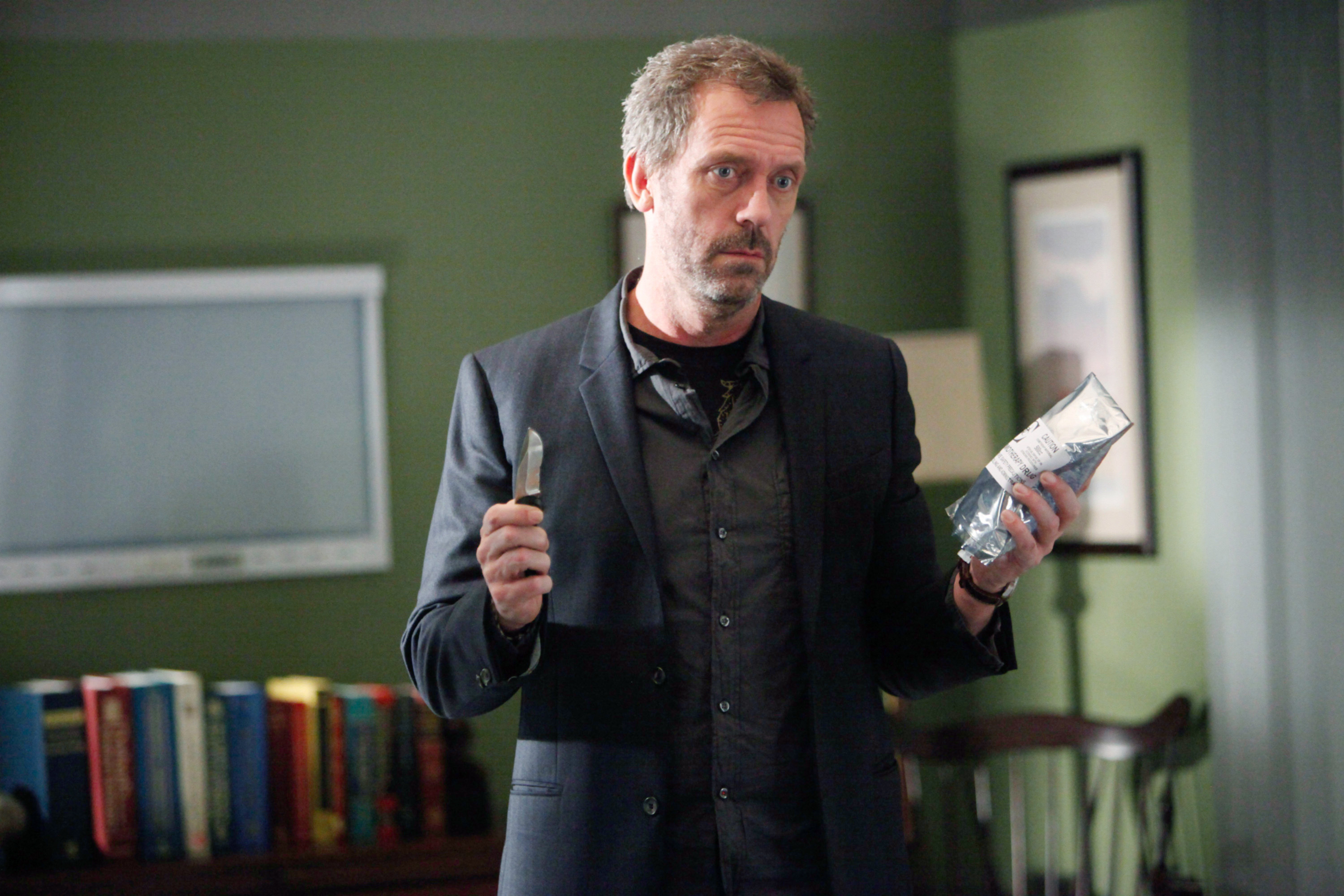 Hugh as House holding a small knife and medical bag