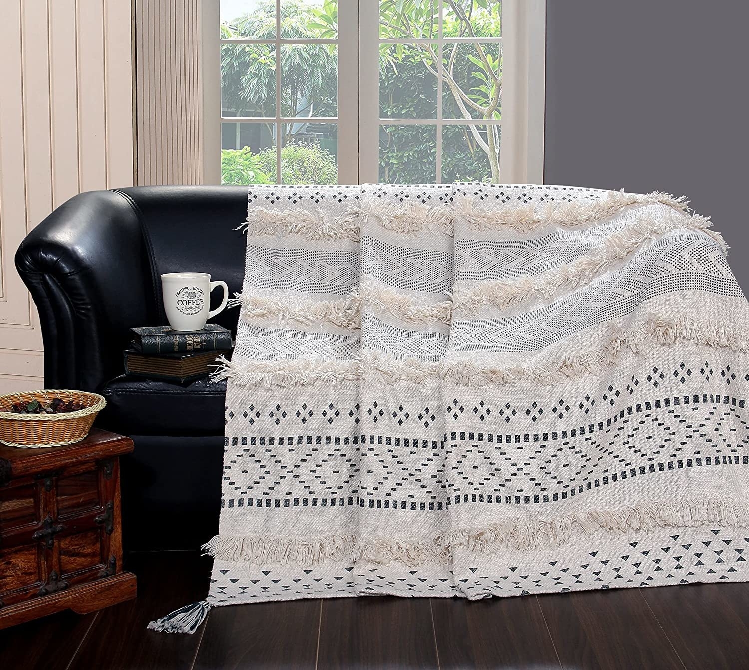A  black and white throw with frills on it and geometric patterns