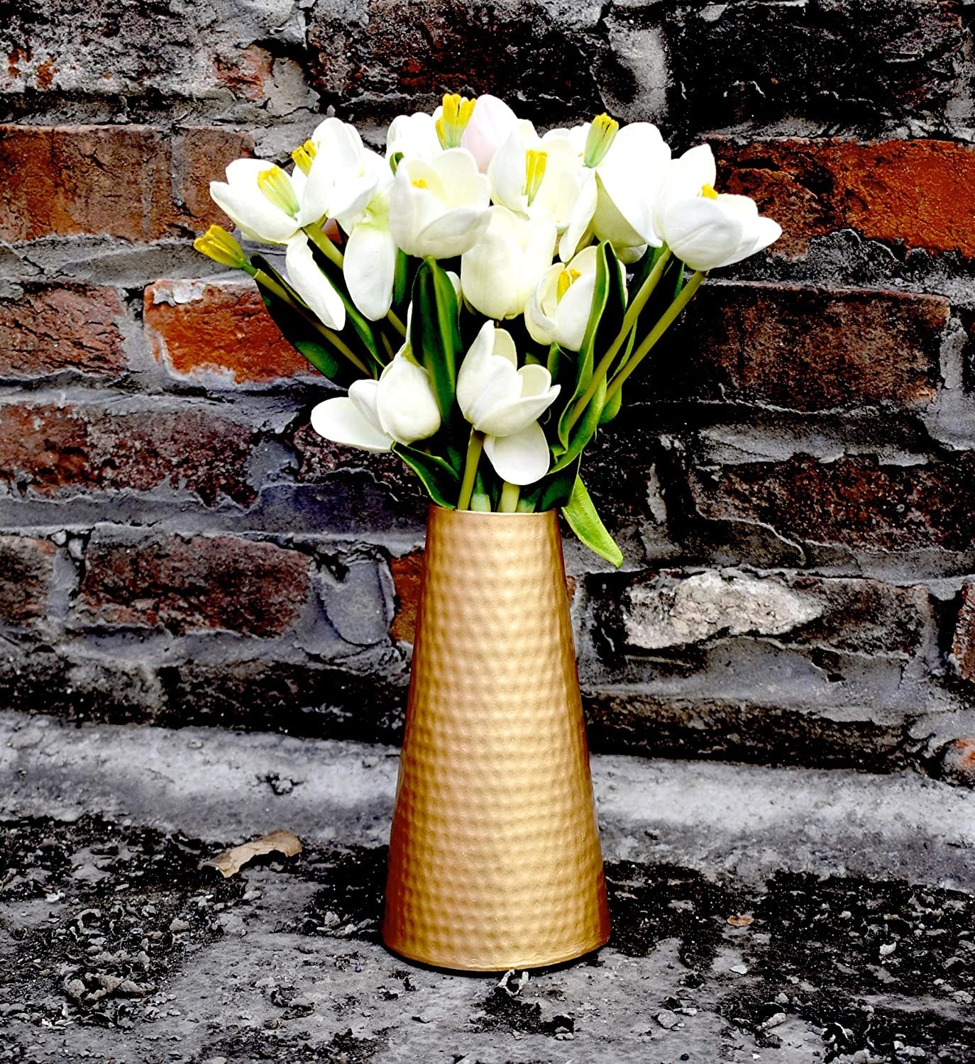 A metal vase in copper colour and white flowers placed in it
