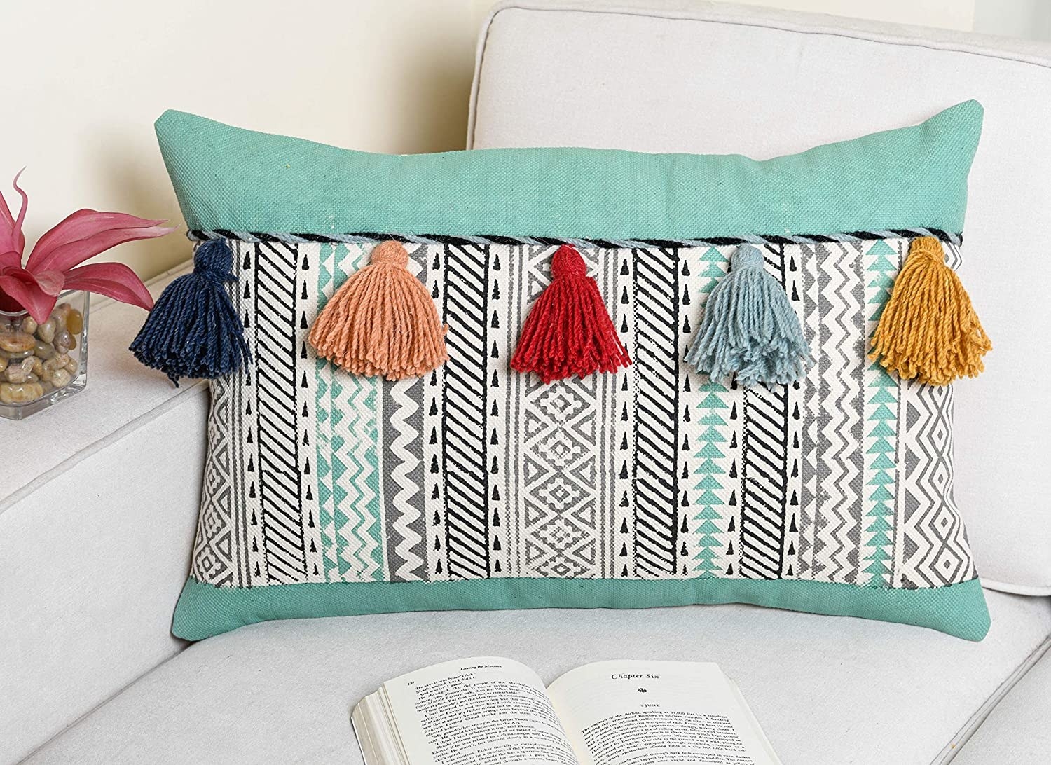 A turquoise cushion cover with colourful tassels on it