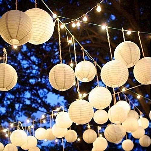 Numerous white hanging lanterns lit up with small yellow bulbs in the night