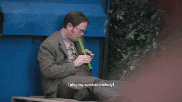 Dwight plays a green recorder next to blue dumpster while Jim and Pam look on