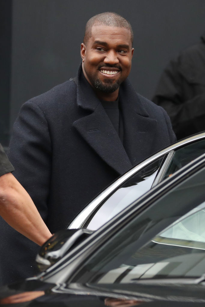 A smiling Kanye about to get into a car