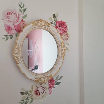 Reviewer's mirror is hung on a wall with a floral rose pattern behind it