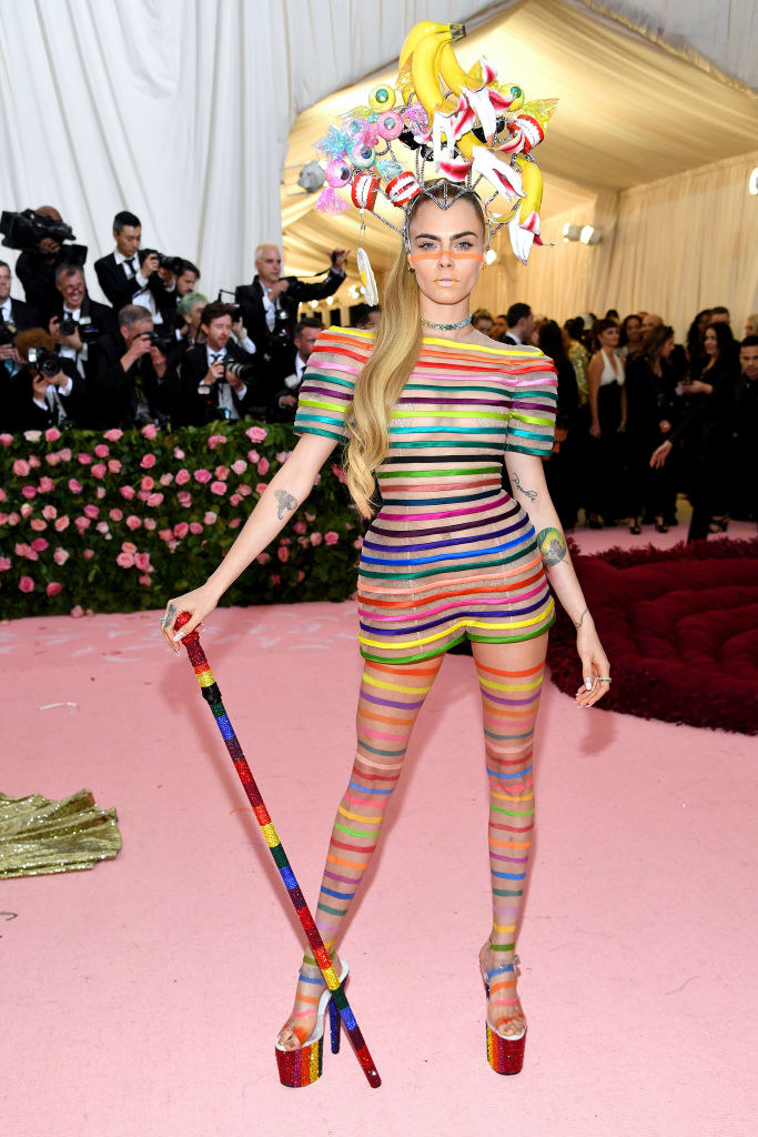 rainbow-striped body suit and a headband with dentures, bananas, and sparkly eyeballs