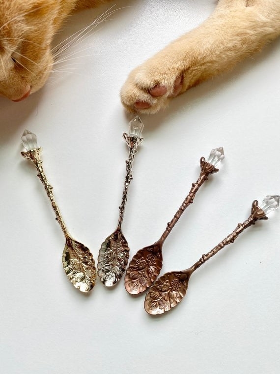Four spoons are displayed in various metals