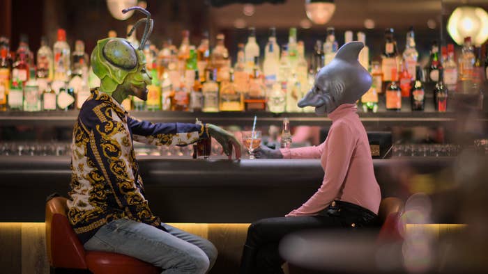 Still from Sexy Beasts of a person dressed as a praying mantis sitting with one dressed as a dolphin