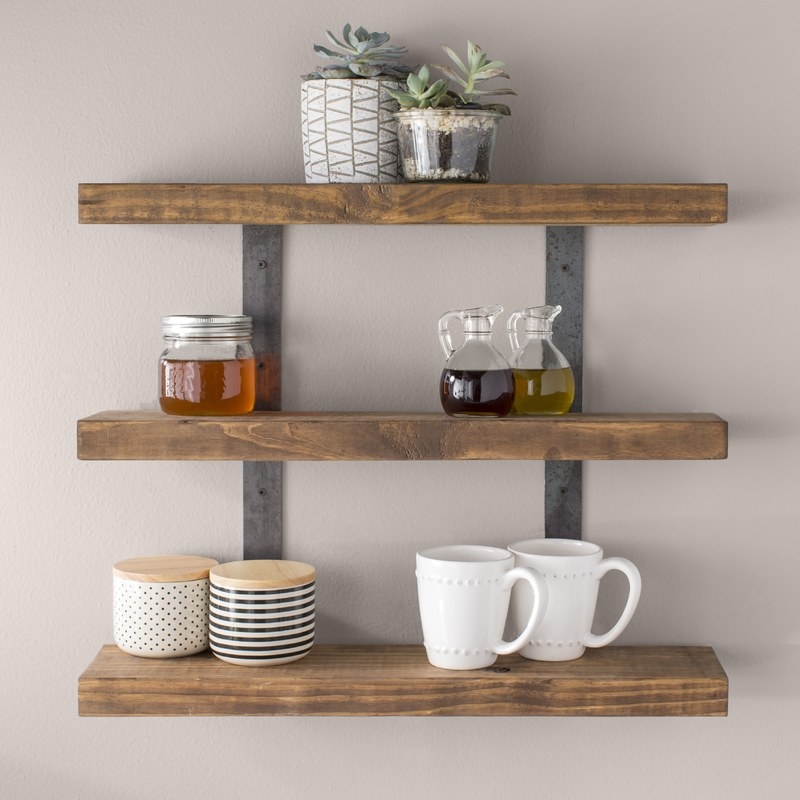 Wall shelf decorated with plants, mugs, canisters, oil, vinegar and honey containers