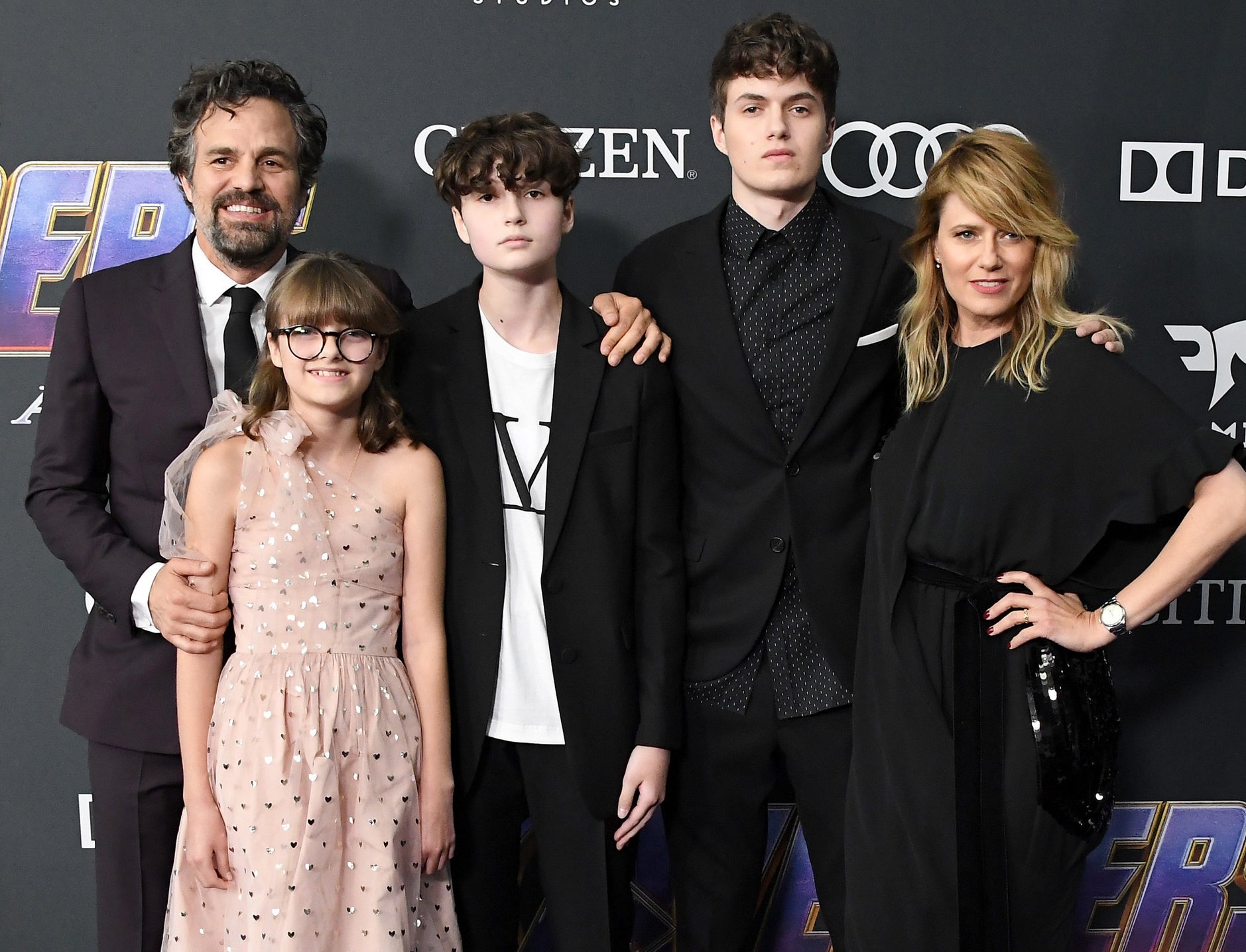Mark and Sunrise pose with their children on a red carpet