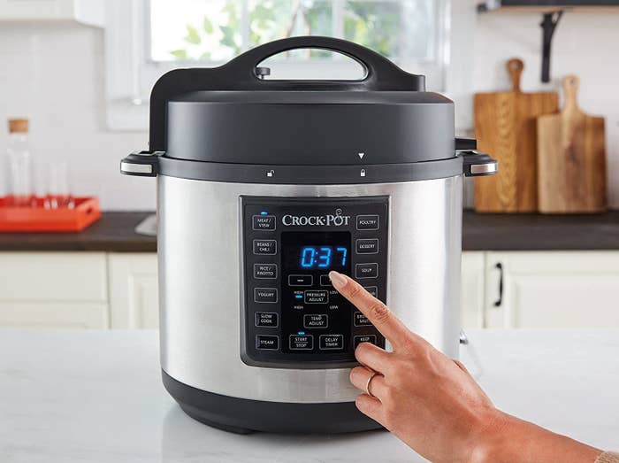 An image of a woman setting the timer on a crock pot