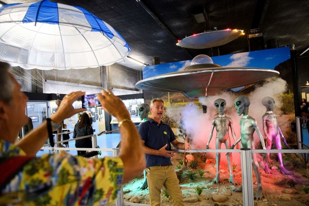 People posing in front of fake aliens at the UFO museum in Roswell