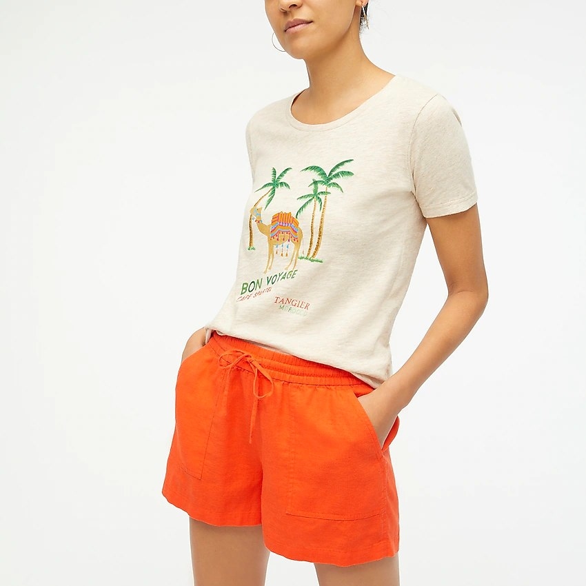 A model wearing the short-sleeve shirt that says &#x27;Bon Voyage&#x27; and has a picture of a camel and palm trees