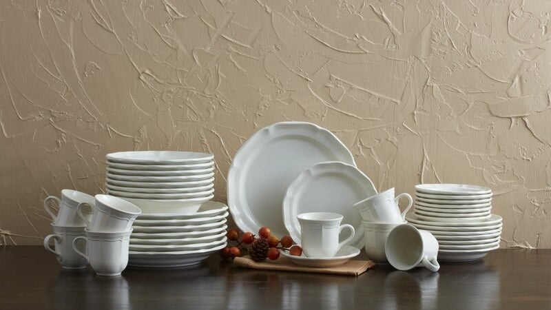 the full set of white dinnerware on a brown table