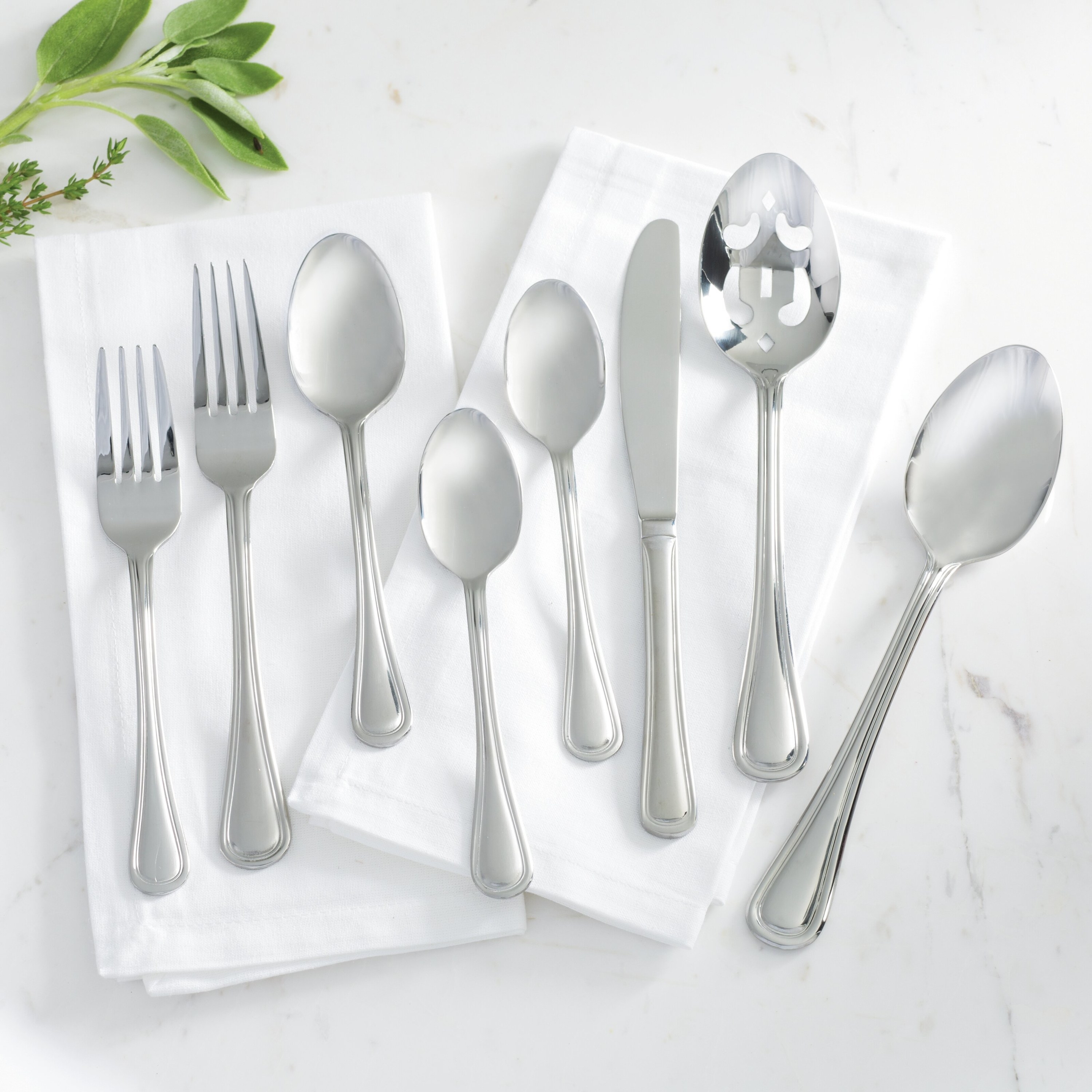 one of each of the forks, knives, and spoons in the set against two white napkins