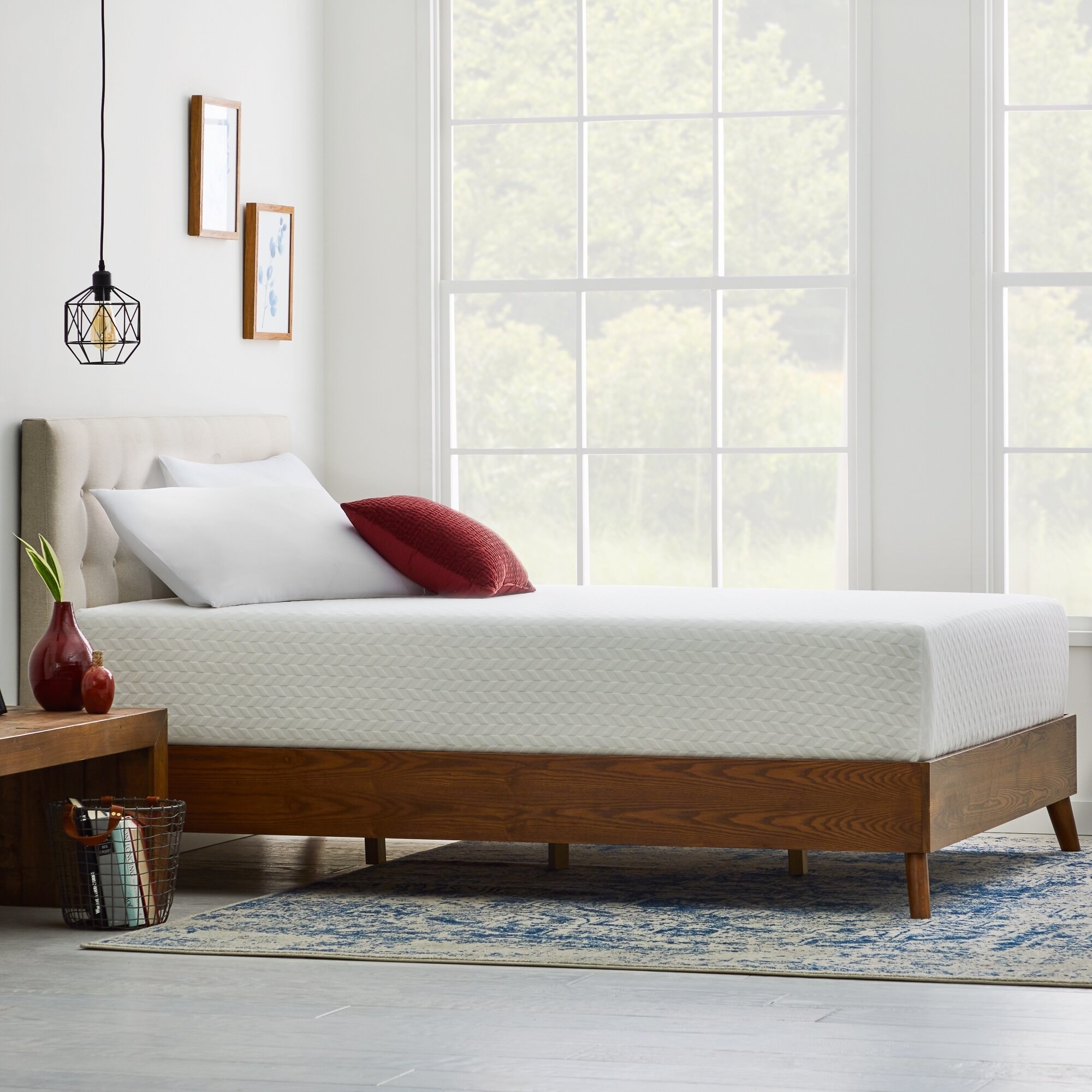 the mattress on a bed frame with white and red pillows stacked on top