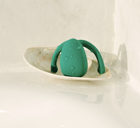 Wet green vibrator on bathtub ledge