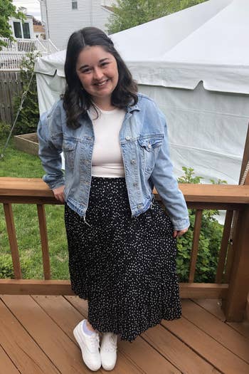 Heather wearing black with white dots skirt with a jean jacket and sneakers