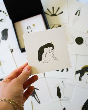 a model holding one of the cards with an illustration of a woman