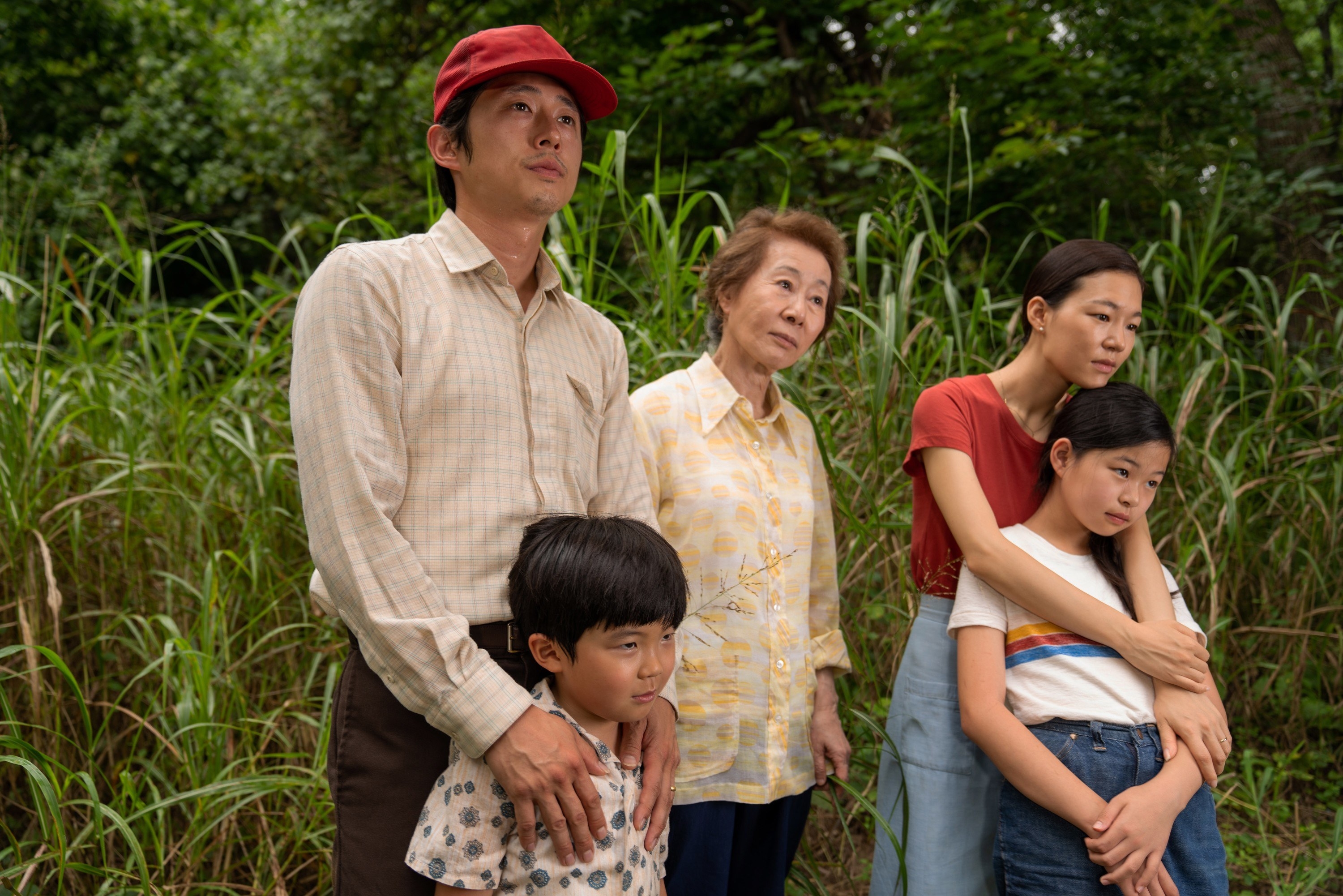 Steven Yeun, Alan S. Kim, Youn Yuh-Jung, Han Yeri, and Noel Cho stand outside in a field