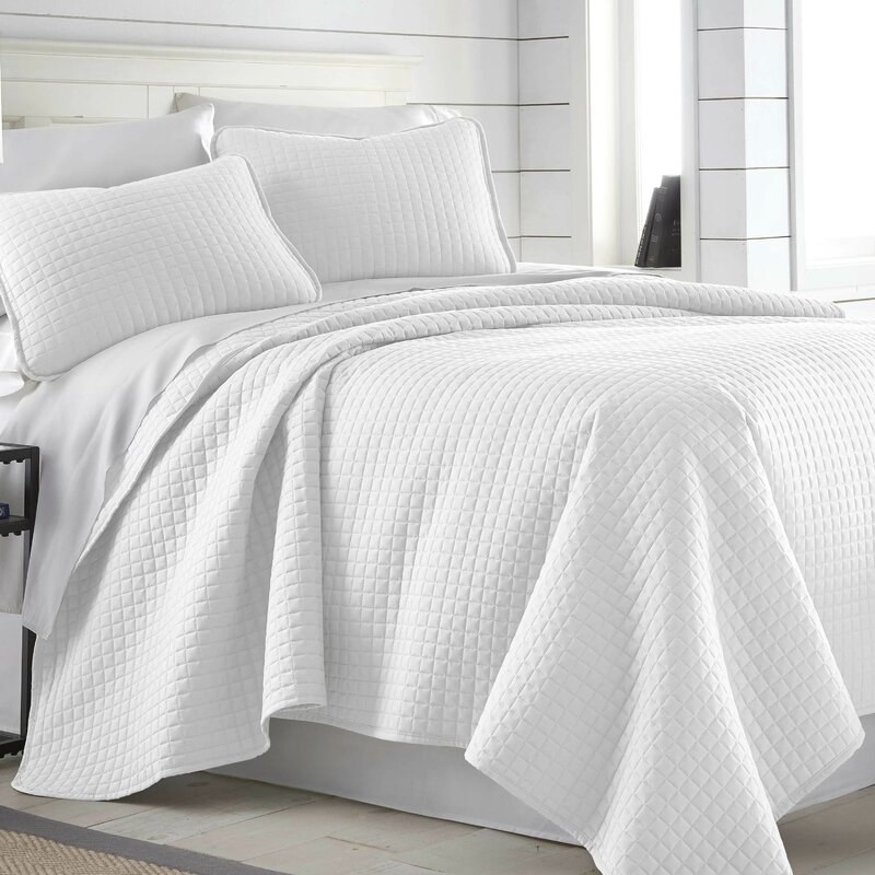 the quilt set on a bed in bright white