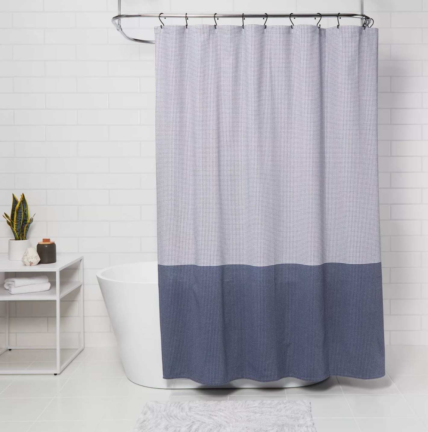 the shower curtain with the top half light blue and bottom half dark blue hanging over a white bathtub