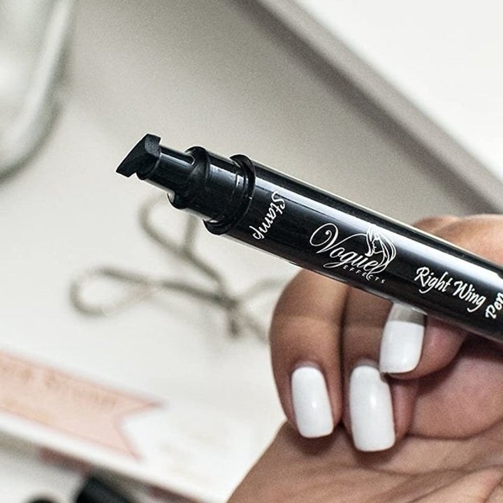 Model holding eyeliner pen with wing-shaped stamp