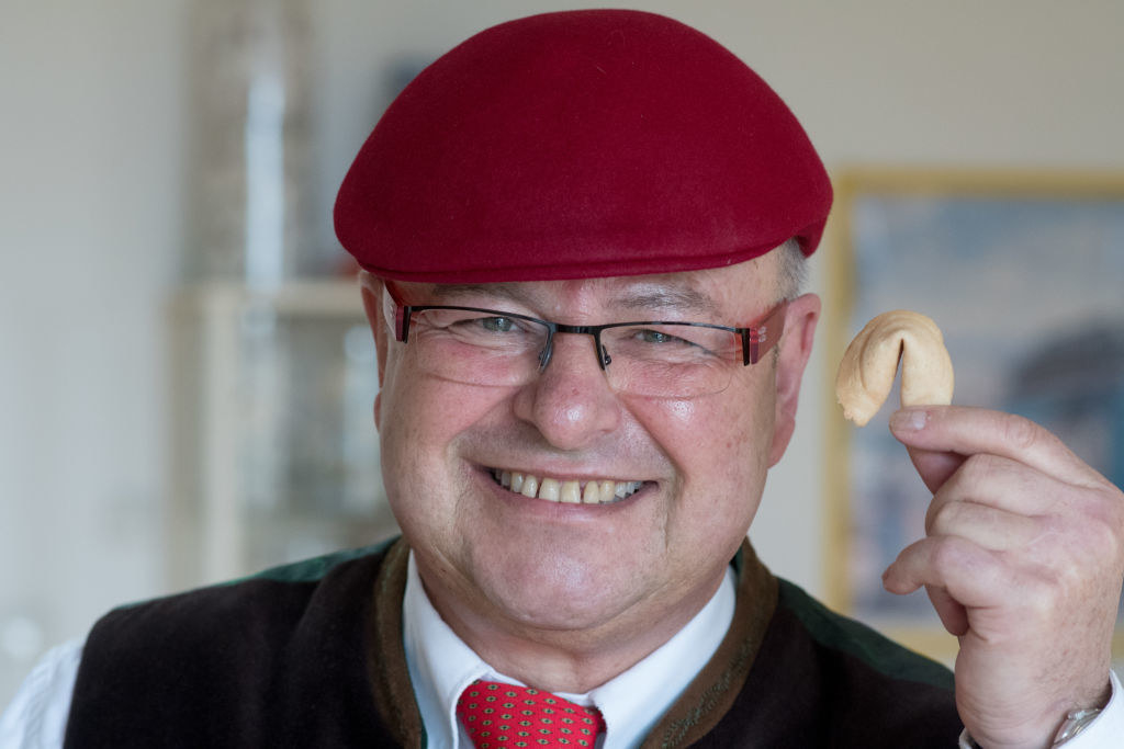 a man smiling and holding up a fortune cookie