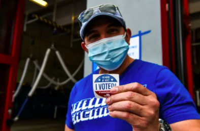 a man holding an i voted! sticker