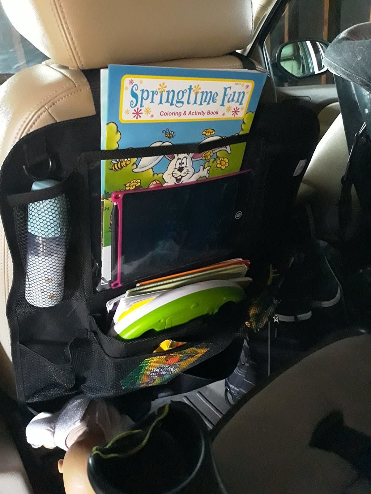 the organizer strapped to the back of a reviewer&#x27;s drivers seat; it has 9 different size storage pockets