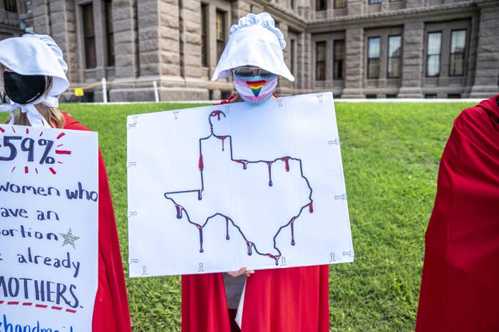 A protester dressed as a handmaiden holds up a sign at a protest outside the Texas state capitol on May 29, 2021