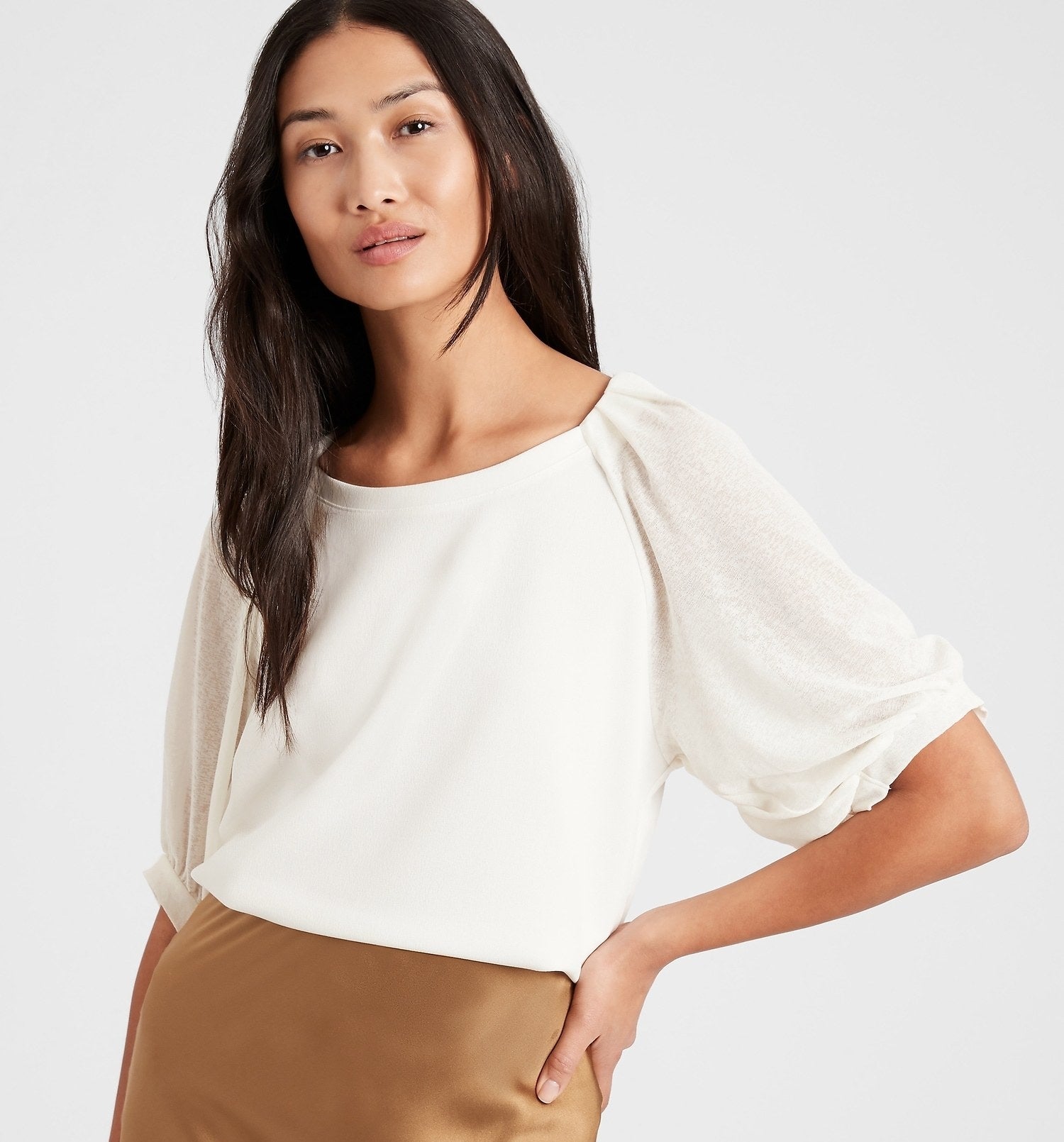 Model is wearing a white top with balloon sleeves and a tan skirt