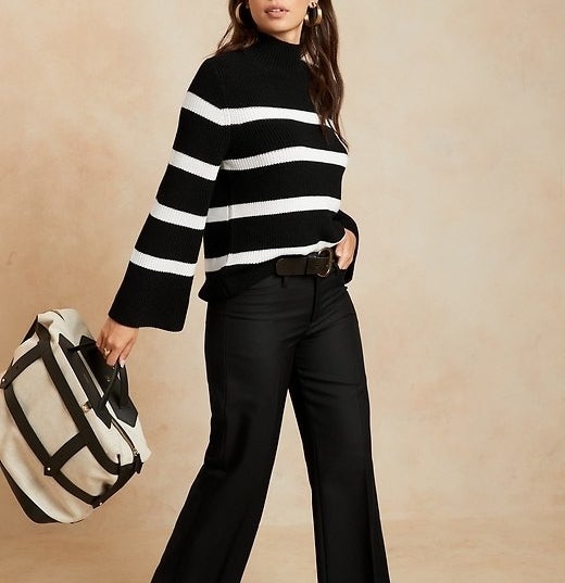 Model is wearing and black and white thick-striped sweater and black trousers
