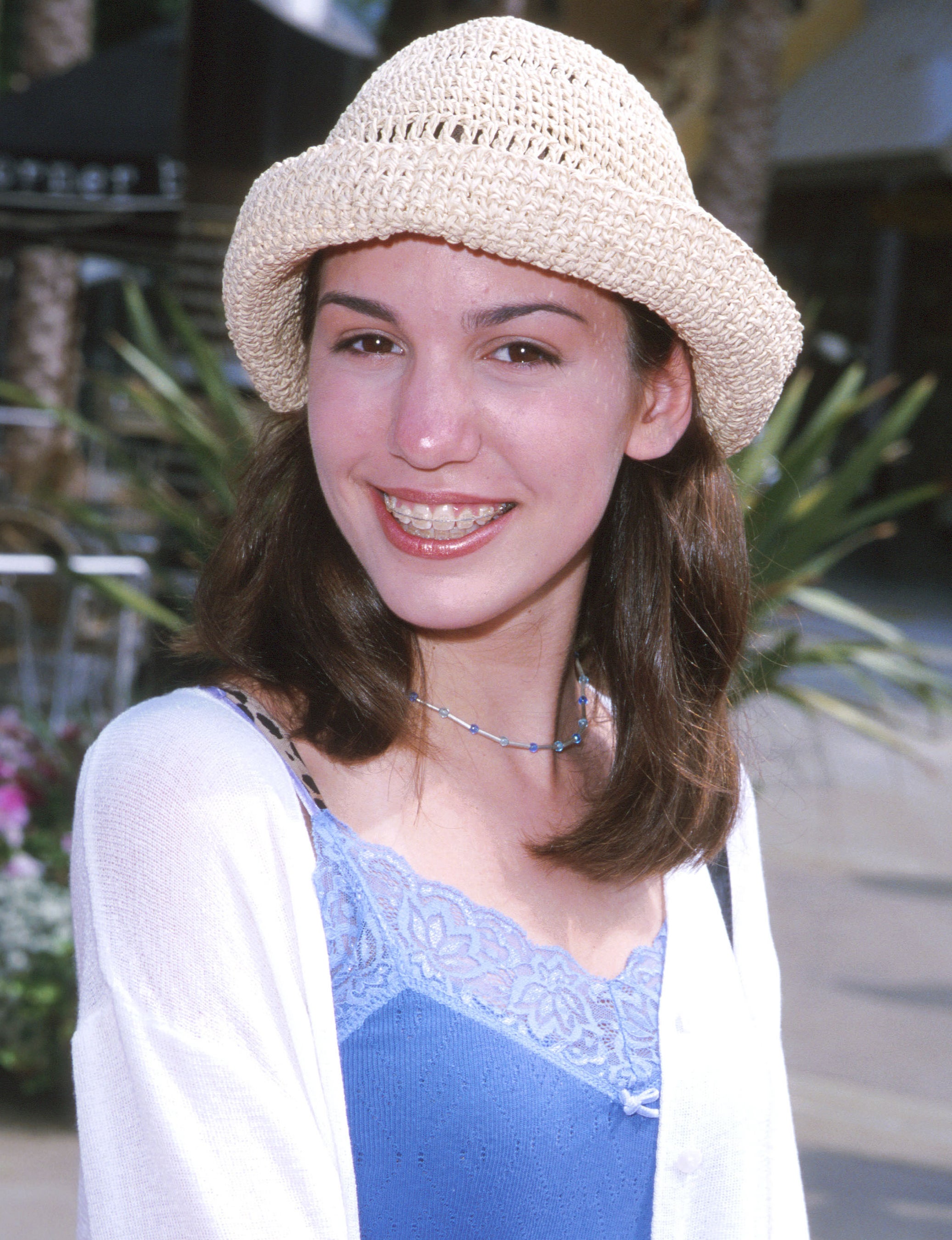 A young Christy has braces and wears a straw hat