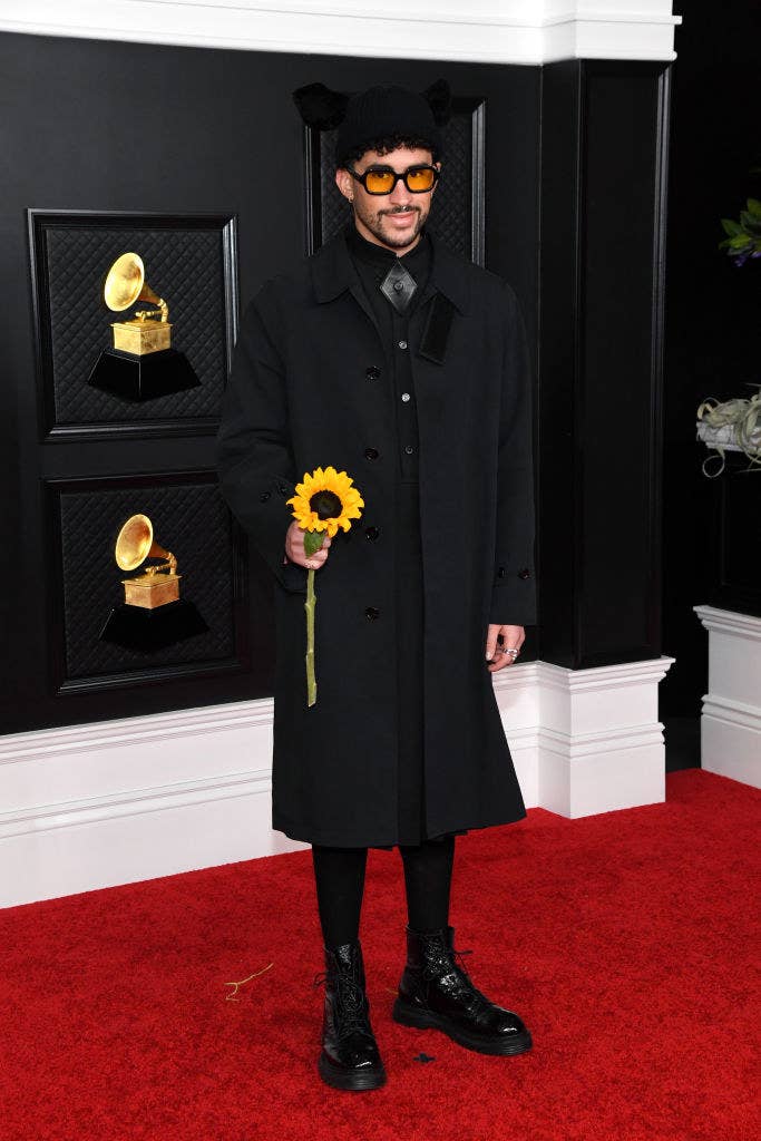 long trenchcoat, bunny ear beanie, and carrying a sunflower