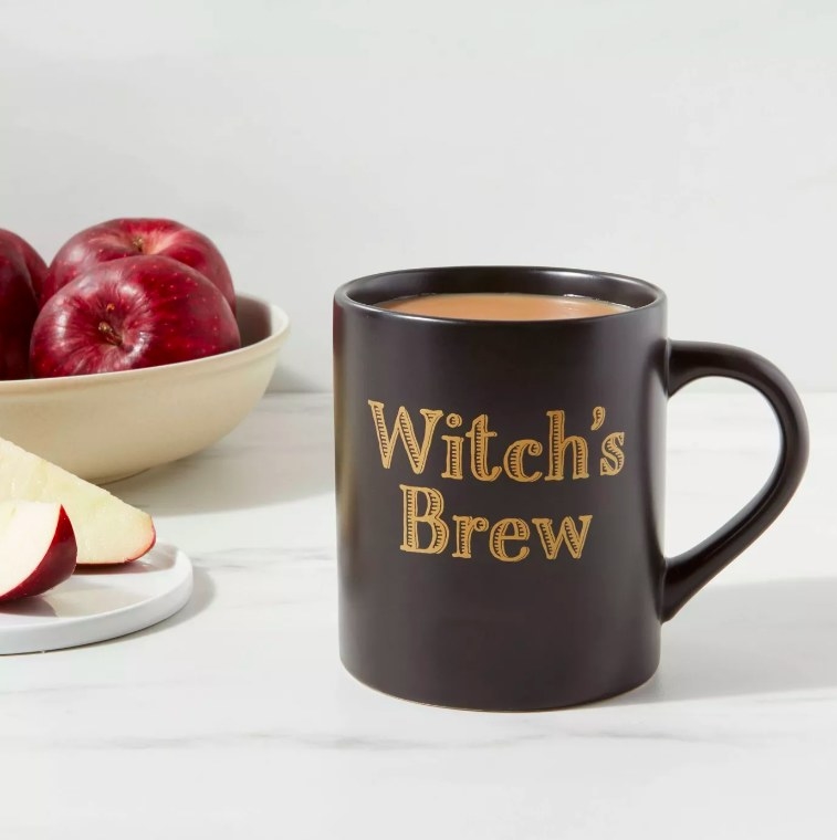 The black mug with &quot;witch&#x27;s brew&quot; in gold lettering
