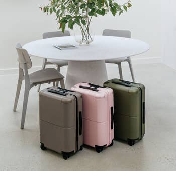 three wheeled carry on suitcases in gray, pink, and olive green 