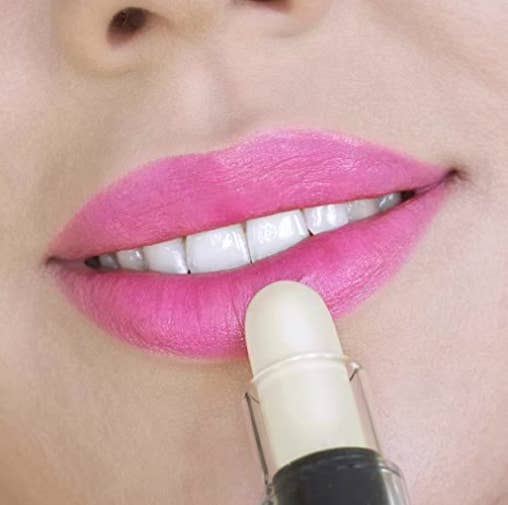 model applying a white lipstick to her lips as it changes to pink  when applied