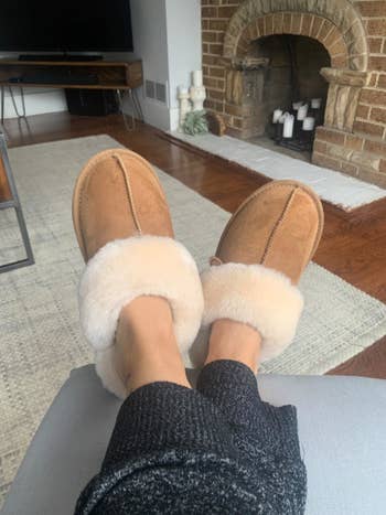 A reviewer wearing the slippers with their feet kicked up