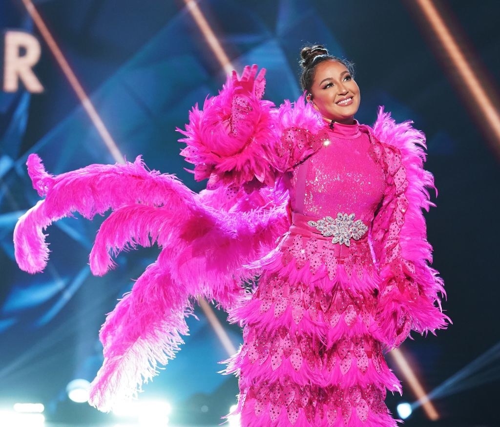Adrienne Bailon Houghton wearing a pink flamingo costume while on stage waving