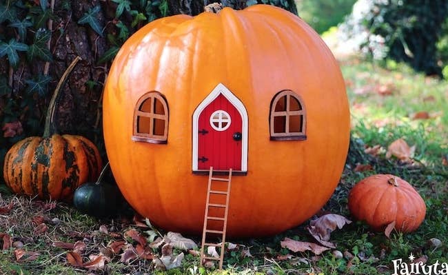 a pumpkin with two windows and a red door on it