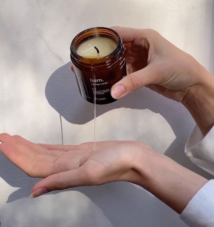 Someone pouring the melted candle into their palm to use as massage oil