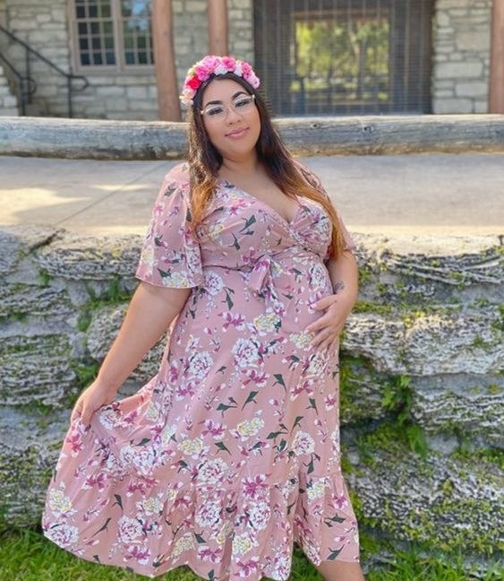 a pregnant reviewer wearing the floral dress in pink