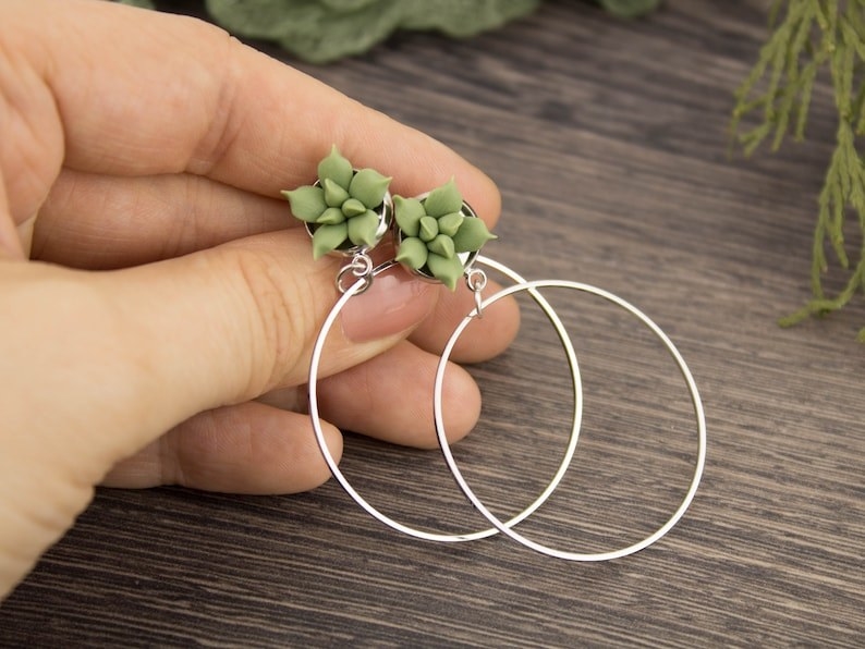 hands holding the large silver hoops with clay succulent design at the top