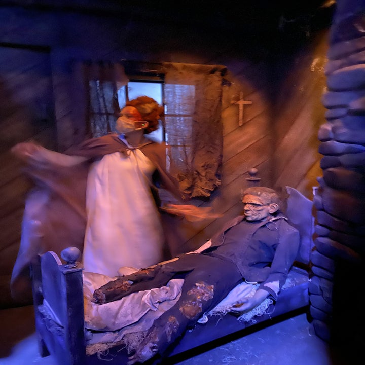 Bride of Frankenstein standing over Frankenstein in bed, his legs cut off