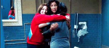 Gina, Rosa, and Amy hugging each other in the bathroom