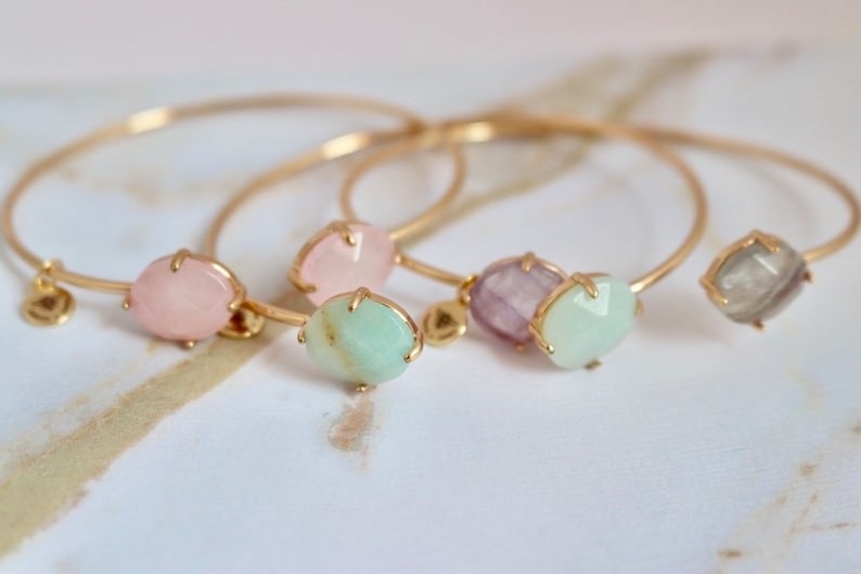 slim gold open cuffs each with two stones in pink, mint, and purple