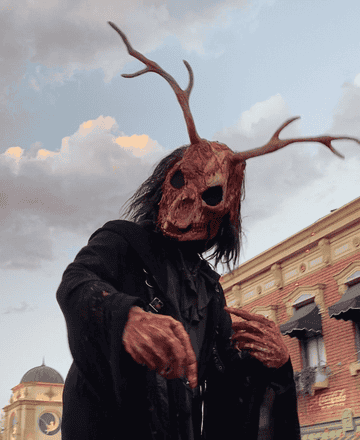 GIF of a monster with a deer skull mask covered in blood reaching out at the camera