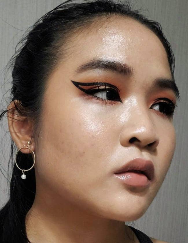 reviewer photo of them wearing black eyeliner in a graphic cay-eye design