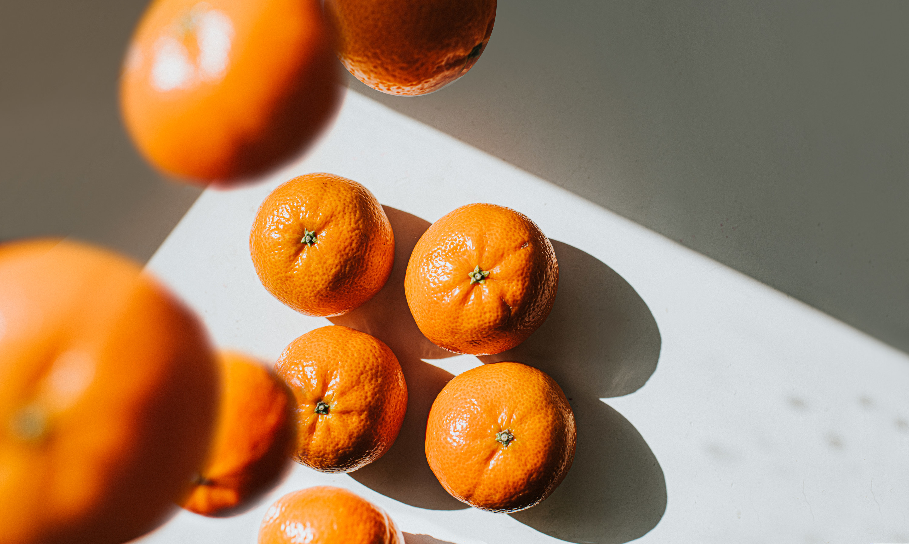 Oranges falling onto a white surface.