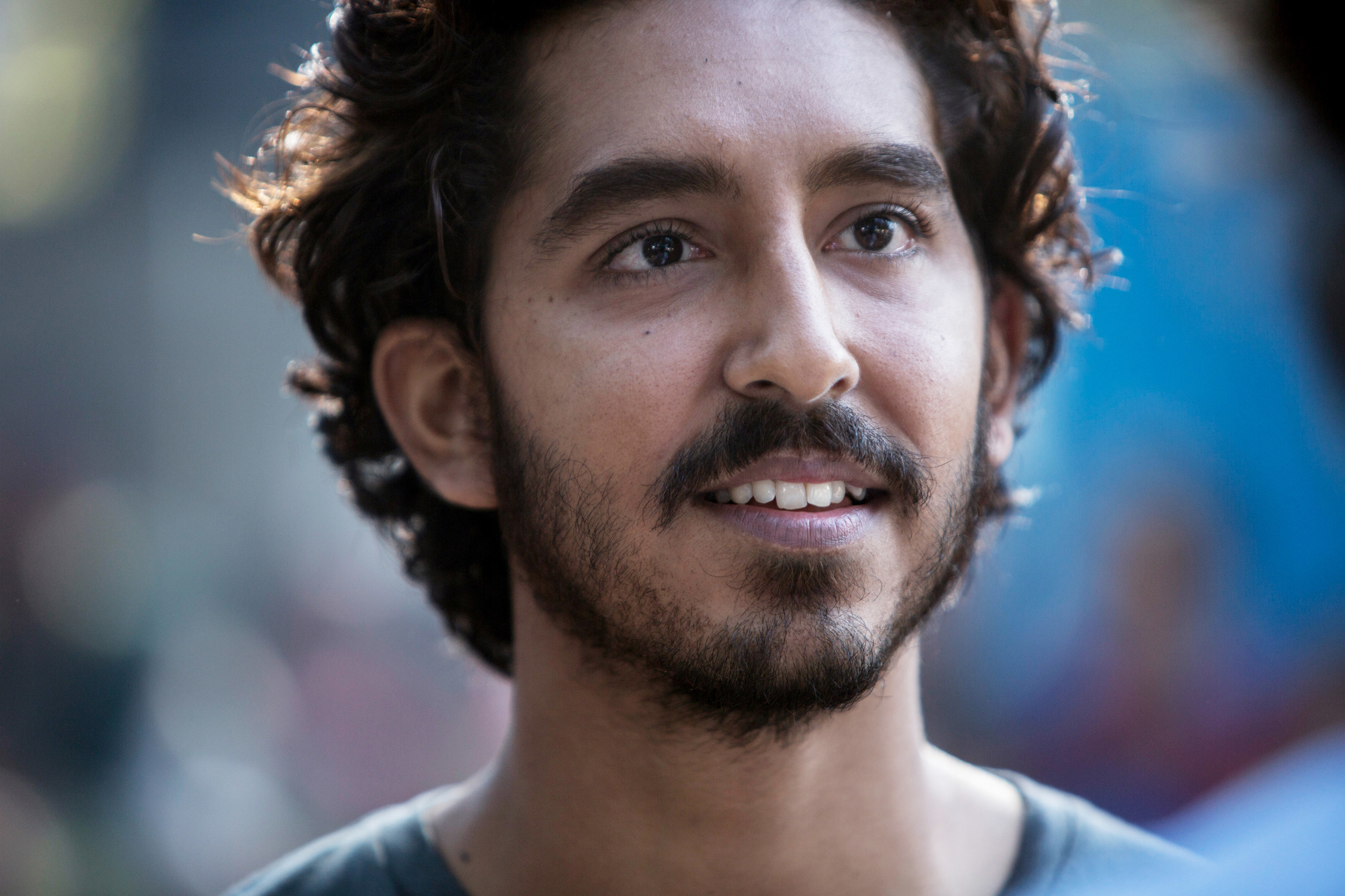 A close up of Dev Patel as he smiles slightly to show his teeth